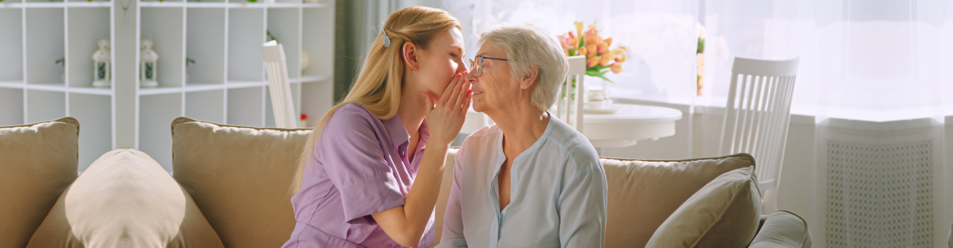 Woman Sharing Secret with Elderly Woman on Sofa
